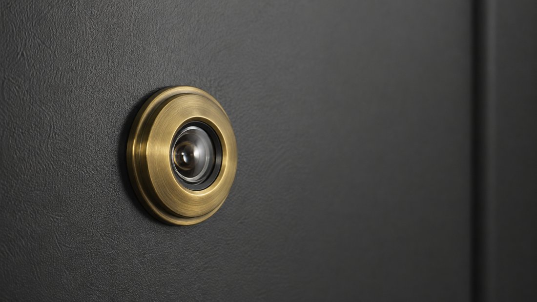 Стеклянный дверной глазок в металлической входной двери, вид снаружи с блестящей передней линзой